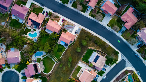 Above view of homes and neighborhoods in the Temecula and Murrieta California in Riverside county with pools, solar panels and tops of roofs with green trees and sun setting light